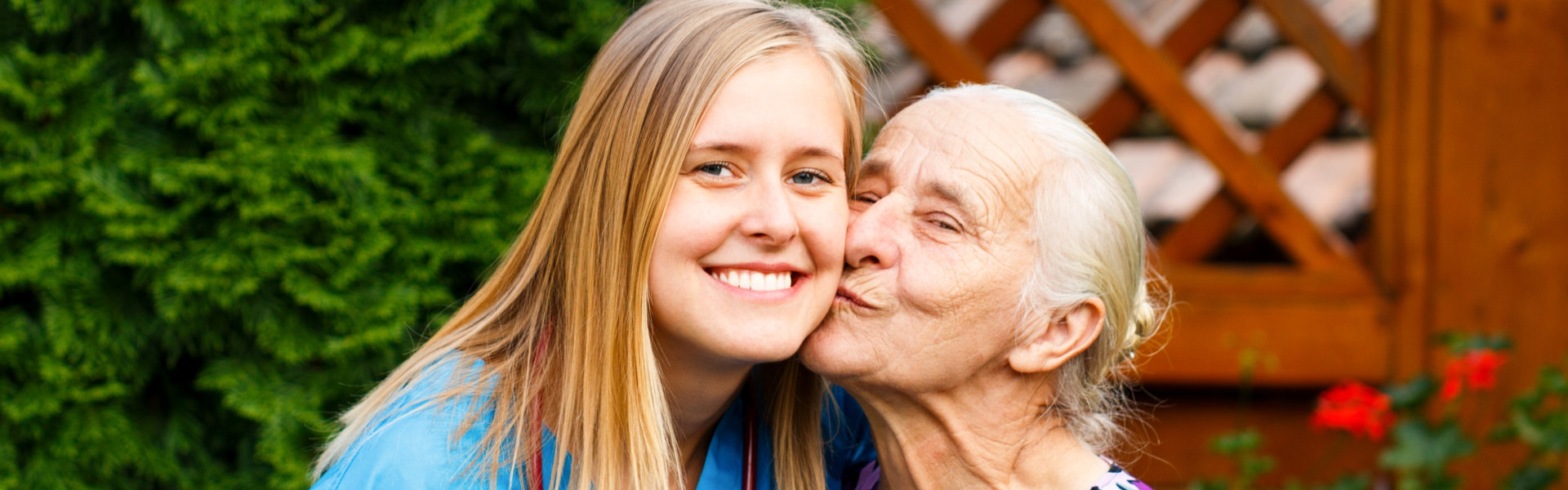 caregiver kissed on cheek by senior woman